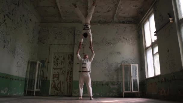 Twee psycho-mannen doen acrobatische trucs, een handstand en een sprong naar beneden in slo-mo — Stockvideo