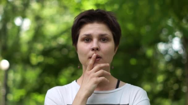 Mujer morena profundamente sorprendida de pie y manteniendo su índice en sus labios en slo-mo — Vídeos de Stock