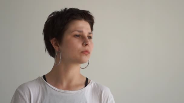 Menina esportiva com nariz piercing sentado e olhando para longe em um estúdio em slo-mo — Vídeo de Stock