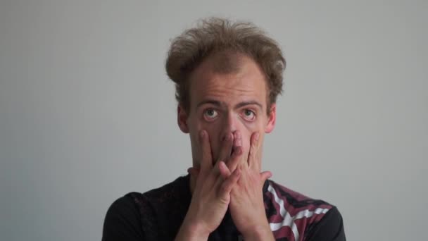 Humorvoller Mann imitiert und macht seine Augen groß wie ein Clown in einem Studio in Slo-mo — Stockvideo