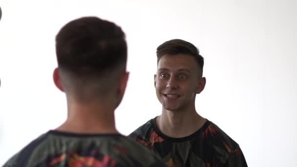 Cheery kille tittar på sin spegelbild och imitera med ett leende i studion i slo-mo — Stockvideo