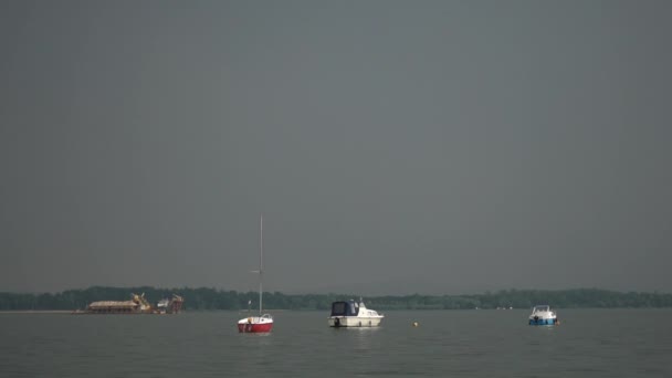 Un petit yacht oscille à la surface de l'eau par temps nuageux . — Video