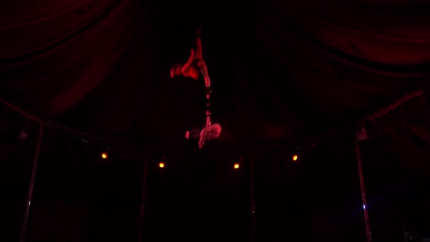Чоловічий акробат тримає дівчаток ноги обертаються і приземляються вночі — стокове відео