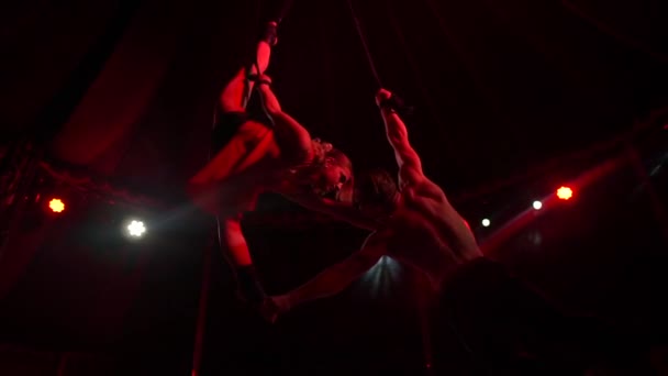 Hombre acróbata tomando una chica con sus pies mientras ella gira en circo por la noche en slo-mo — Vídeo de stock