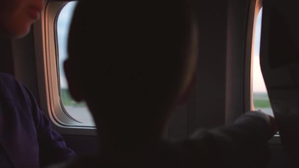 Mutter mit Kind sitzt am Fenster des Flugzeugs, während das Flugzeug abhebt — Stockvideo