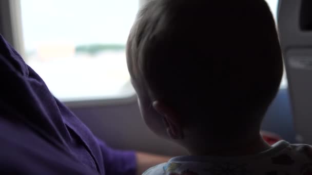 Мама с ребенком у окна самолета сидит и ждет взлета . — стоковое видео