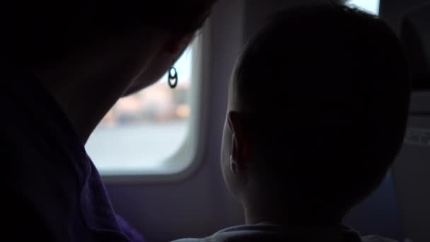 母亲带着孩子靠近飞机窗口坐在一起，等待起飞. — 图库视频影像