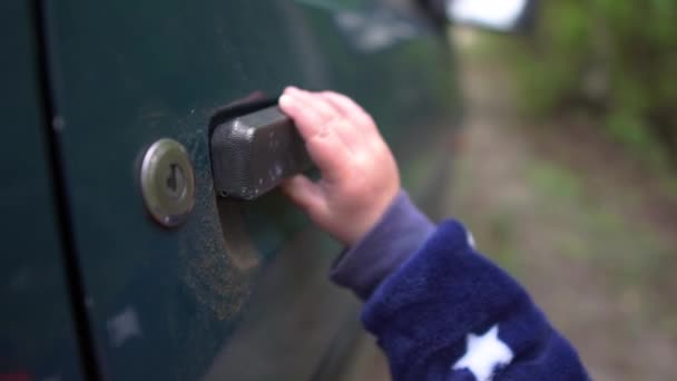 Kisbaba próbál megnyitni egy régi autó fogantyú a szabadban tavasszal slo-Mo — Stock videók
