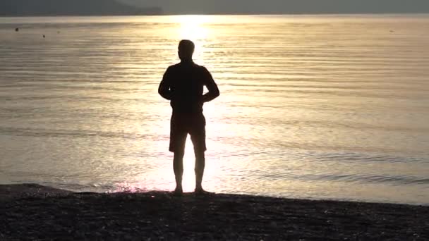 Mannen gör positiv gest med handen, tummen upp på bakgrunden av havet — Stockvideo