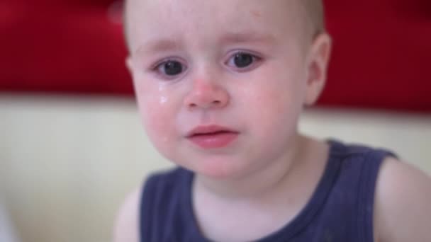 Little blond boy cries, sitting on the bed in the room, slow motion — Stock Video