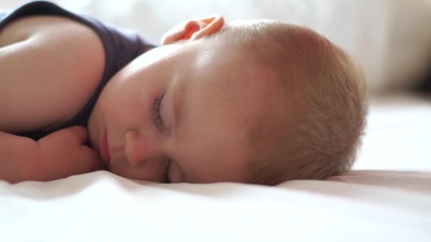 Маленький блондин сладко спит на большой кровати в замедленной съемке. — стоковое видео