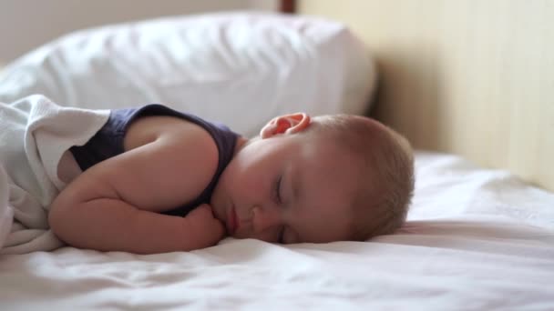 Pequeño niño lindo está durmiendo dulcemente en una cama grande en cámara lenta — Vídeos de Stock