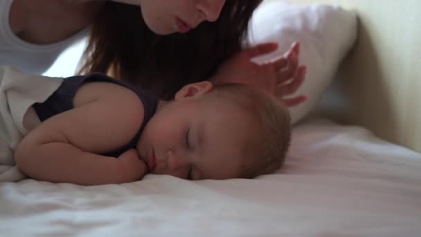 Mãe beija o bebê na bochecha enquanto ele dorme docemente em câmera lenta — Vídeo de Stock