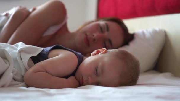 Mamá y el bebé duermen dulcemente juntos en una cama grande durante el día en cámara lenta — Vídeos de Stock