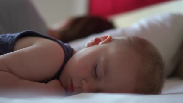Мама и малыш сладко спят вместе на кровати днем в замедленной съемке. — стоковое видео
