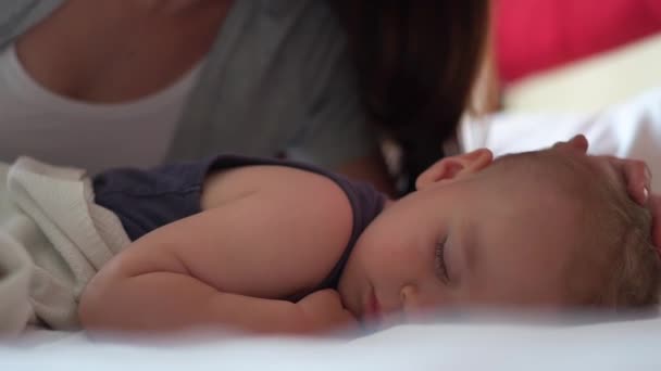 Mamá acaricia la cabeza de los hijos mientras él duerme dulcemente en una cama grande en cámara lenta — Vídeo de stock