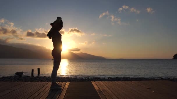4k - スローモーションで海でエネルギー練習を行う日没時の女性のシルエット — ストック動画