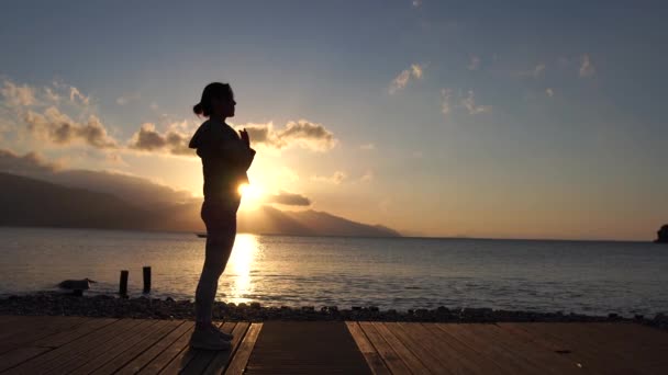 4k - La joven al atardecer practicando la energía junto al mar en cámara lenta — Vídeos de Stock