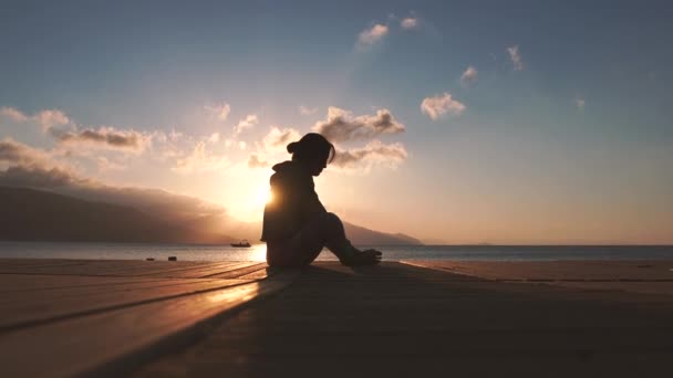 4K-Girl gör ben massage i kalv vid solnedgången vid havet i slow motion — Stockvideo