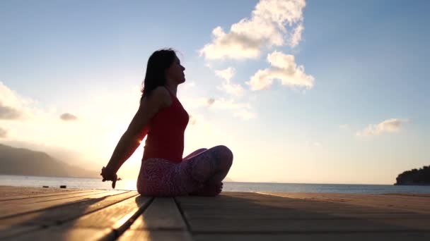 4k-jong meisje doet oefeningen in de buurt van de zee bij zonsopgang in slow motion — Stockvideo
