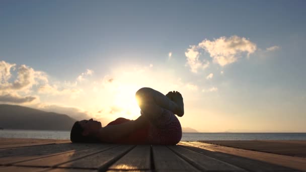 4k - 女性はスローモーションで海の海辺の木製のポンツーンでピラティスを練習します — ストック動画