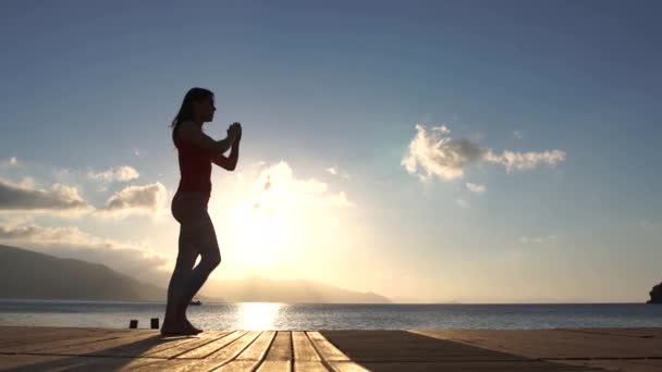 4k - una mujer hace ejercicios de fitness cerca del mar de la mañana en cámara lenta — Vídeos de Stock
