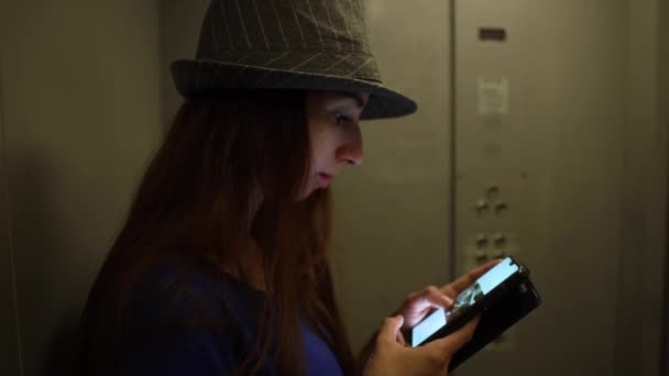 Menina de cabelo marrom elegante movendo-se no elevador e navegar na rede em seu telefone — Vídeo de Stock