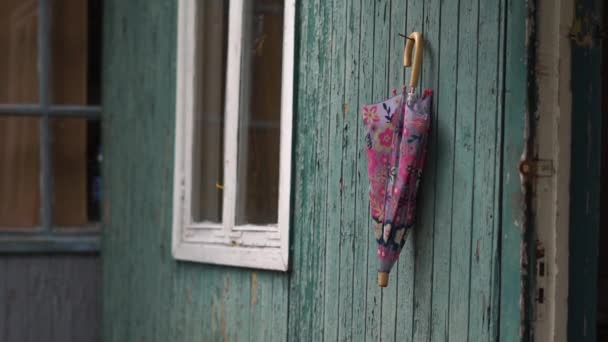 Kleurrijke paraplu opknoping op een houten handvat van een kleine schuur in een bos in de zomer — Stockvideo