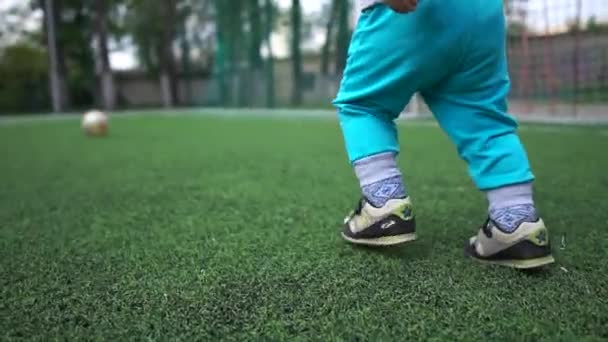Garoto alegre correndo em um campo de futebol para uma grande bola na primavera em slo-mo — Vídeo de Stock