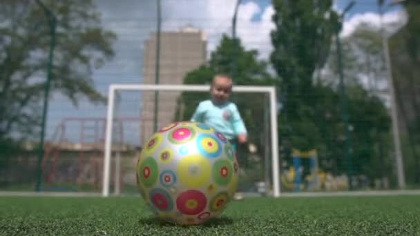 Bambino divertente che gioca con una palla su un campo di calcio in una giornata di sole in estate a Slo-mo — Video Stock