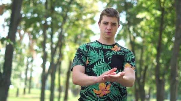 Komik adam bir parkta dururken ellerini çırpıyor — Stok video