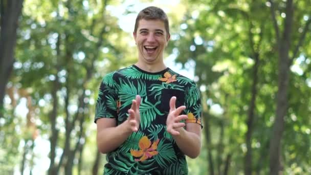 Funny guy claps his hands like an idiot standing in a park — Stock Video