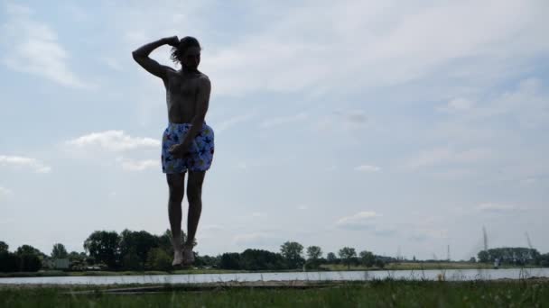 Молодой веселый мужчина прыгает на батуте и позирует смешно в замедленной съемке — стоковое видео
