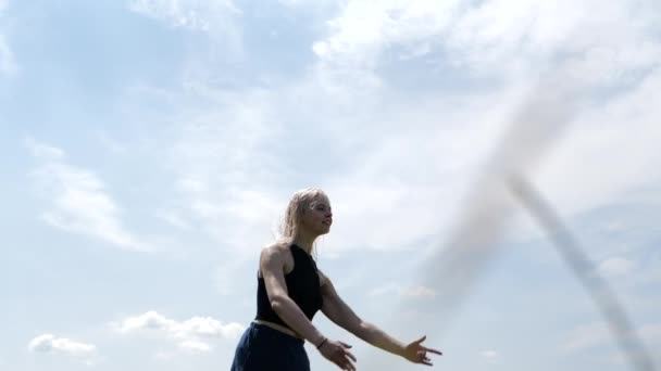 Jeune fille blonde faisant de la ficelle dans les airs dans un saut sur un trampoline contre le ciel — Video