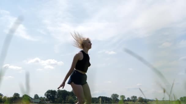 Sonriente chica saltando en un trampolín y haciendo cordel en el aire, cámara lenta — Vídeo de stock