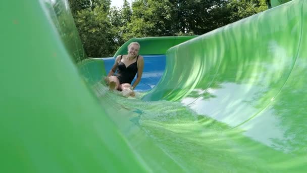 Lächelnde junge Frau steigt im Freien in Zeitlupe von einer Wasserrutsche ab — Stockvideo