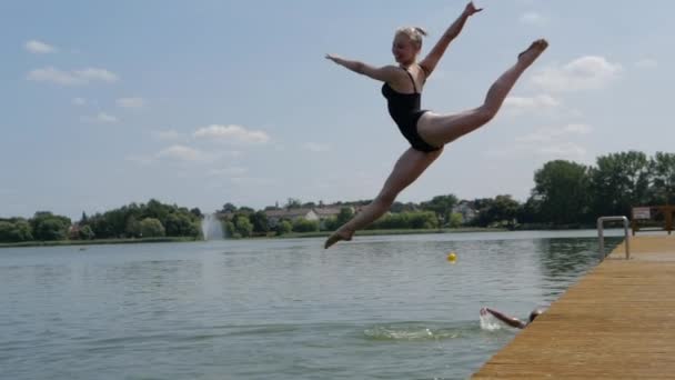 Dívka skákající z mola do řeky, dělá ve vzduchu vlákna, pomalý pohyb — Stock video