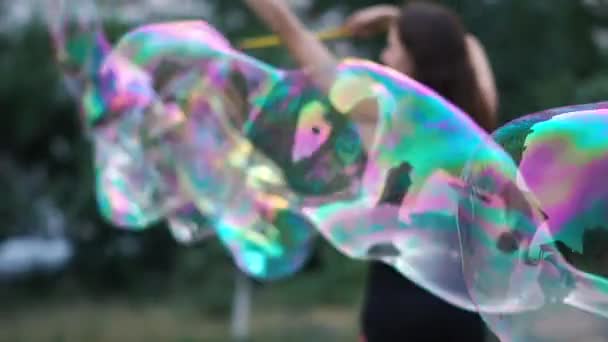 Brunette girl creates incredibly beautiful soap bubbles in the square in slow motion — Stock Video