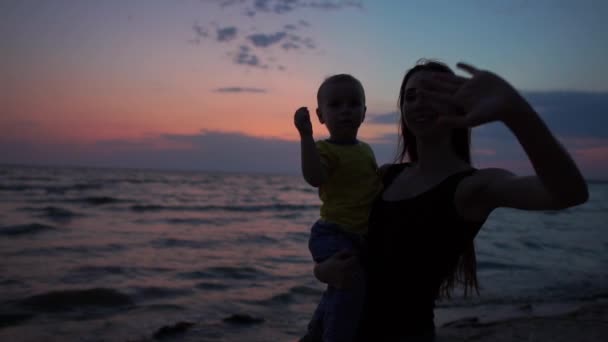 Молода мати з довгим волоссям тримає сміливу дитину на руці — стокове відео
