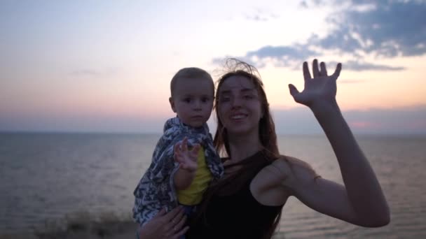 Mutter und ihre Sonne bei Sonnenuntergang am Meer. — Stockvideo