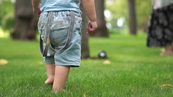 Kleine barefoot jongen rent in slow motion op het gras in het park — Stockvideo