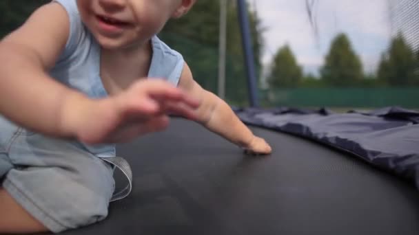 Leende baby på studsmatta sparkar kameran vid foten i slow motion — Stockvideo