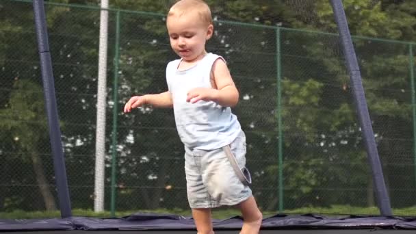 Sonriente niño saltando cae en un trampolín en cámara lenta — Vídeo de stock