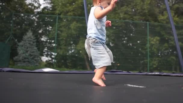 Neşeli küçük çocuk ağır çekimde tramboline atlıyor. — Stok video