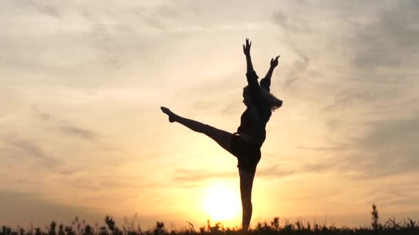 Giovane ragazza ballerina bionda fare spago al tramonto al rallentatore. — Video Stock