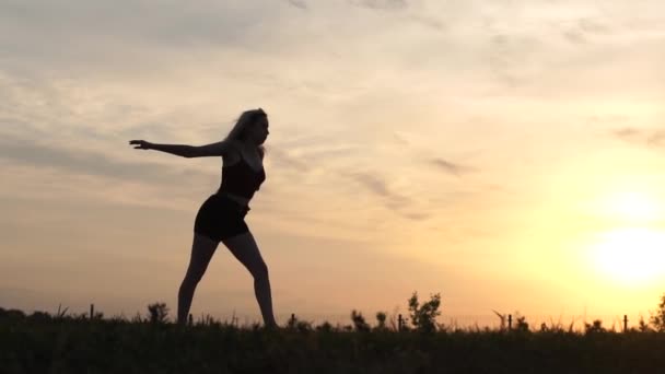 Silhouette di danza ragazza salta e si piega in un salto al rallentatore — Video Stock