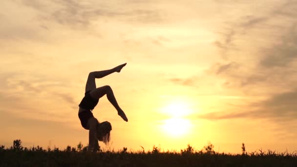 Úžasná dívka akrobat při západu slunce provádí handstand - zpomalený film. — Stock video