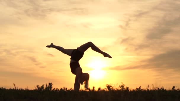 Gadis penari saat matahari terbenam melakukan handstand gerakan lambat. — Stok Video
