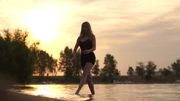 Een jonge danseres maakt in slow motion twine op het meer, de actie vindt plaats bij dageraad. — Stockvideo