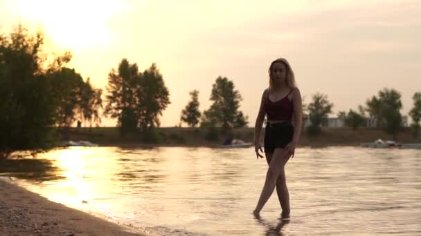 Schattig blond girle dans bij zonsopgang in de buurt van het meer. — Stockvideo